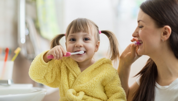 Mom and young daughter brushing their teeth to prevent cavities